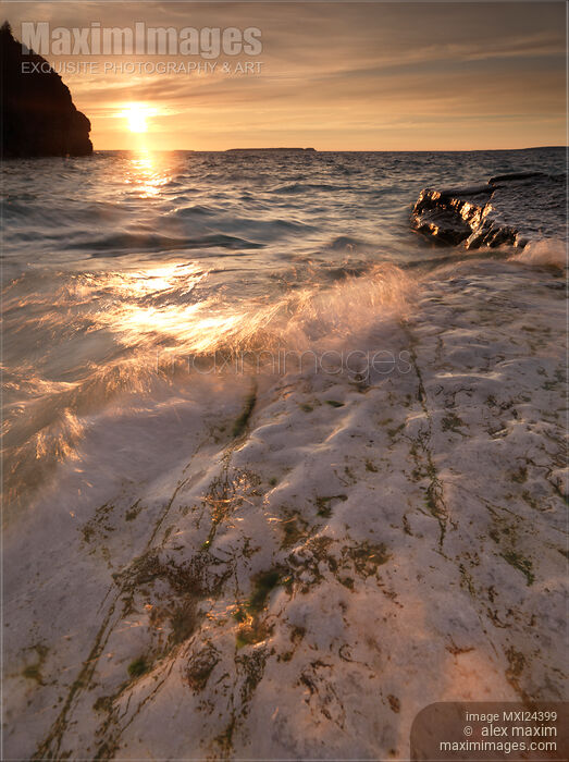Stock photo of Sunset nature scenery of waves hitting rocky shore Buy commercial use license at MaximImages