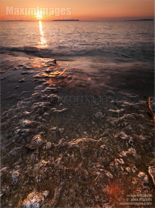 Stock photo of Sunset scenery of waves hitting rocks Buy commercial use license at MaximImages