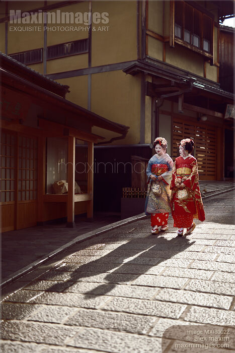 Stock photo of Two Geisha apprentices Maiko in bright kimono walking down an old street in Kyoto Japan Buy commercial use license at MaximImages