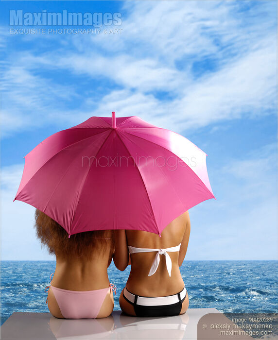 Two women sitting together under umbrella on sea shore Stock photo of Two women sitting together under umbrella on sea shore Buy commercial use license at MaximImages