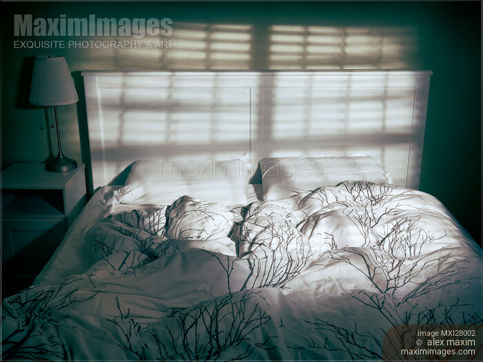 Stock photo of Unmade empty bed in dramatic lighting Buy commercial use license at MaximImages