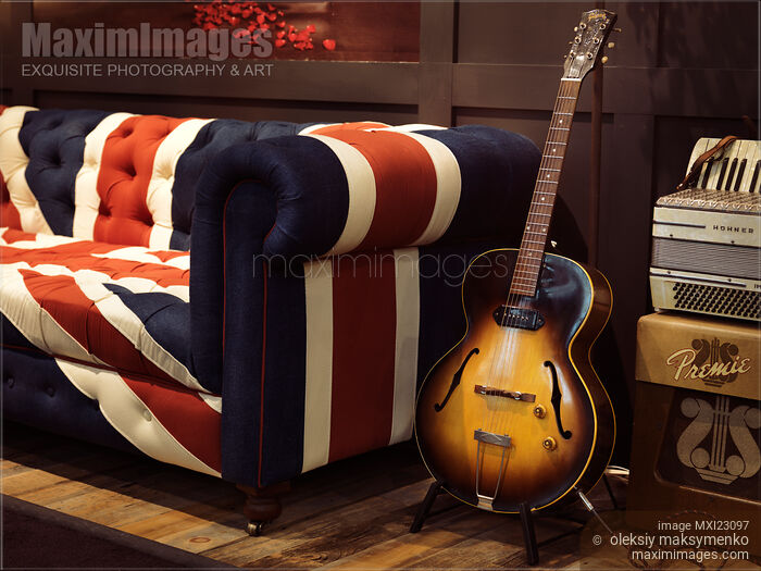 Stock photo of Vintage Acoustic Guitar at a Sofa Buy commercial use license at MaximImages