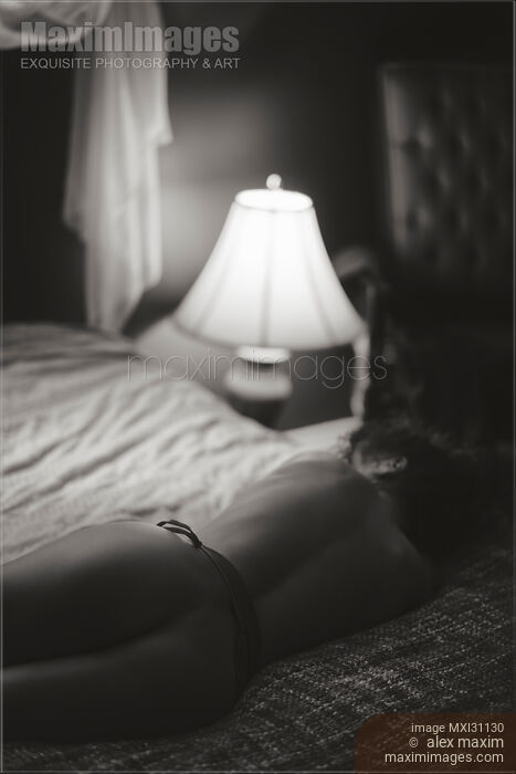 Vintage art nude portrait of the back of a beautiful naked woman lying on the bed in dim light Stock photo of Vintage art nude portrait of the back of a beautiful naked woman lying on the bed in dim light Buy commercial use license at MaximImages