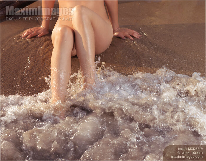 Water washing over legs of a young woman sitting naked on a beach Stock photo of Water washing over legs of a young woman sitting naked on a beach Buy commercial use license at MaximImages
