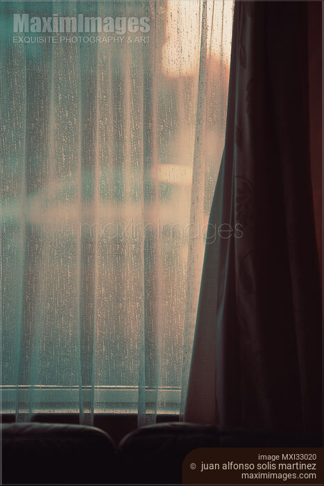 Stock photo of Window behind a sheer curtain in a dark home mysterious indoor scenery Buy commercial use license at MaximImages