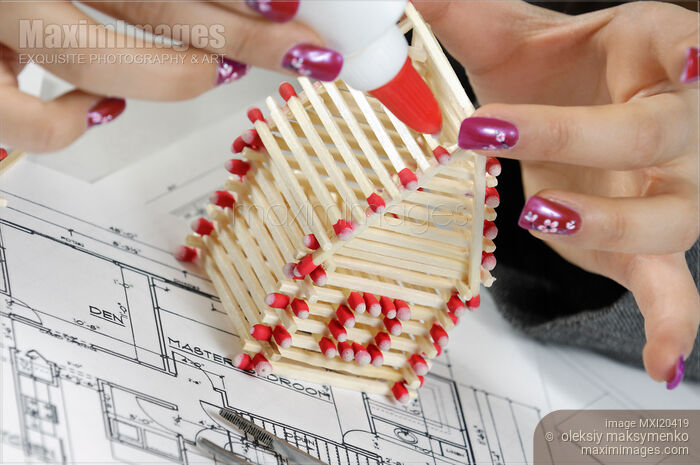 Stock photo of Woman Building a House from Matches Buy commercial use license at MaximImages