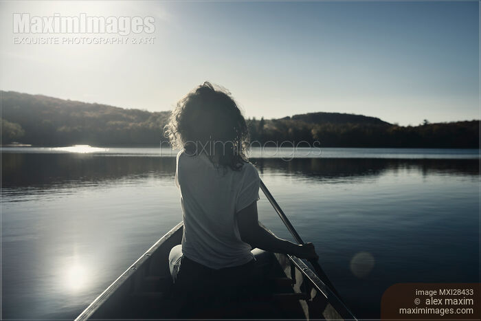 Stock photo of Woman canoeing on a lake Buy commercial use license at MaximImages