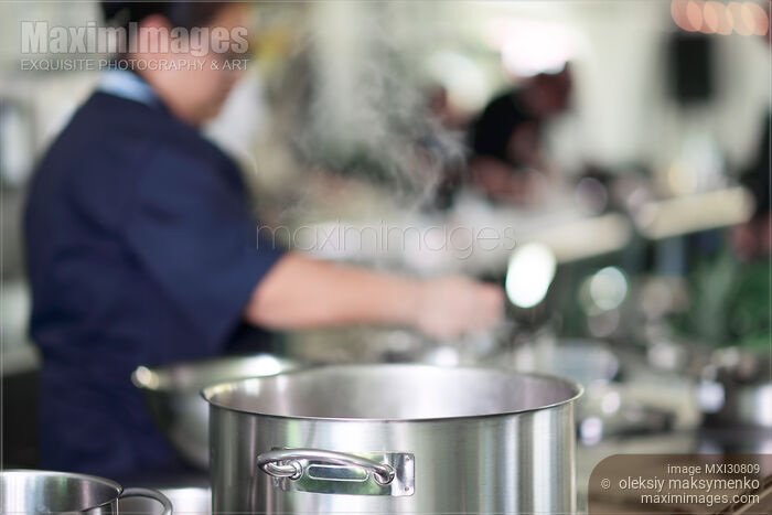 Stock photo of Woman Chef behind a steaming pot in a kitchen Buy commercial use license at MaximImages