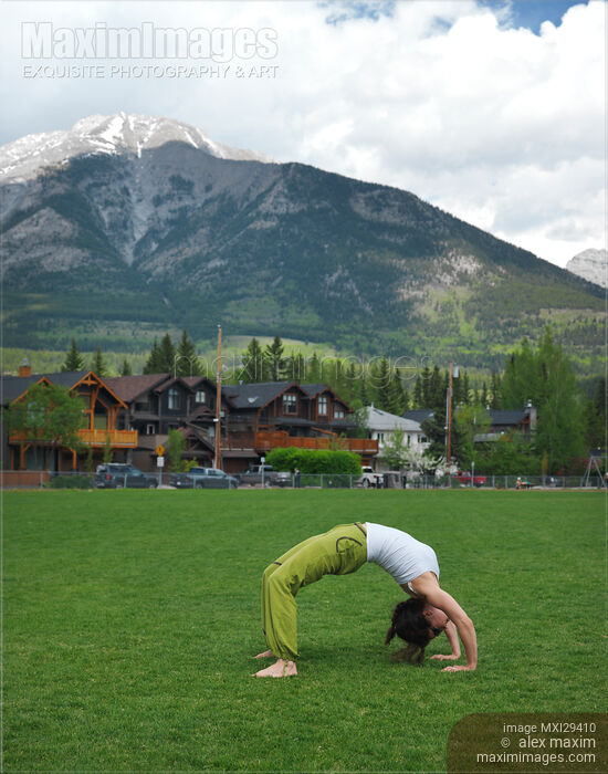 Stock photo of Woman doing bridge yoga posture in a park in Canmore Alberta Buy commercial use license at MaximImages