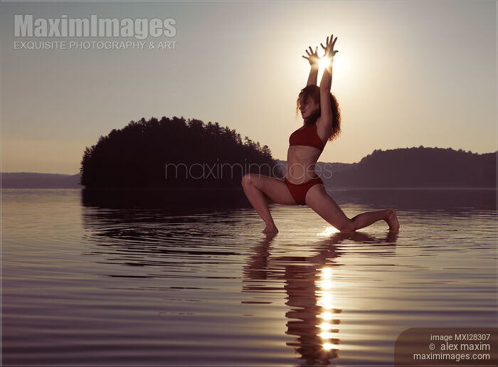 Stock photo of Woman doing yoga Anjaneyasana Low Lunge pose on the water in morning sunlight Buy commercial use license at MaximImages