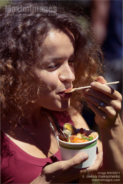 Stock photo of Woman eating street food enjoyment at BC seafood festival in Canada Buy commercial use license at MaximImages