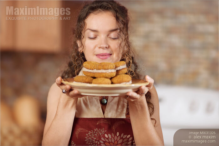 Stock photo of Woman enjoying smell of fresh home-made baked cookies in the kitchen Buy commercial use license at MaximImages