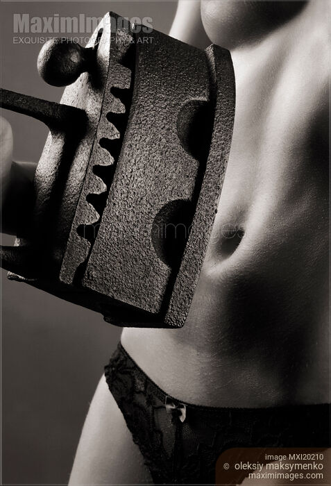 Stock photo of Woman holding antique flat iron in front of her bare stomach Buy commercial use license at MaximImages