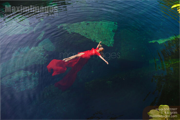 Woman in beautiful red dress lying on clear blue water Aerial fine art photograph Stock photo of Woman in beautiful red dress lying on clear blue water Aerial fine art photograph Buy commercial use license at MaximImages