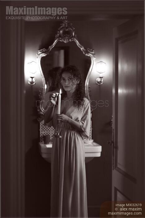 Woman in evening gown lighting a candle in her hand with a mysterious look Black and White boudoir portrait Stock photo of Woman in evening gown lighting a candle in her hand with a mysterious look Black and White boudoir portrait Buy commercial use license at MaximImages