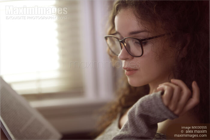 Woman in glasses reading a book by the window Stock photo of Woman in glasses reading a book by the window Buy commercial use license at MaximImages