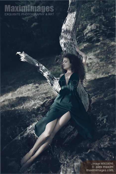 Woman in green dress lying on a dried tree with a dreamy relaxed expression Stock photo of Woman in green dress lying on a dried tree with a dreamy relaxed expression Buy commercial use license at MaximImages