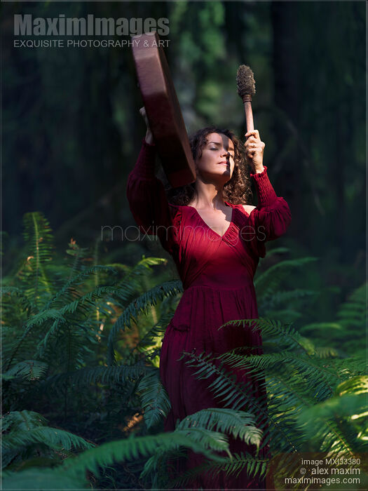 Woman in red dress beating shamanic drum in tranquil dark forest nature scenery Stock photo of Woman in red dress beating shamanic drum in tranquil dark forest nature scenery Buy commercial use license at MaximImages