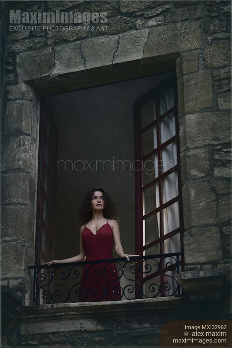 Woman in red dress standing in an open window in a French stone house looking outside at night Stock photo of Woman in red dress standing in an open window in a French stone house looking outside at night Buy commercial use license at MaximImages