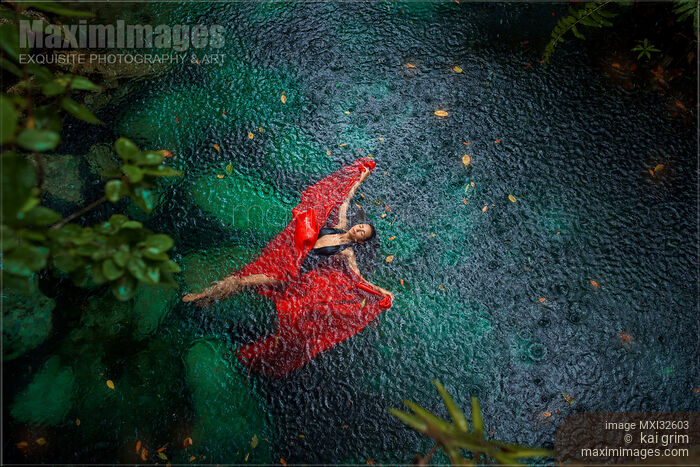 Woman in swimsuit and red dress lying on blue water in the rain Beautiful aerial fine art photograph Stock photo of Woman in swimsuit and red dress lying on blue water in the rain Beautiful aerial fine art photograph Buy commercial use license at MaximImages