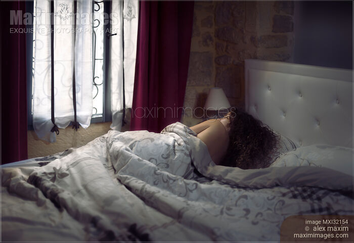 Woman lying asleep in bed in the morning covered with a blanket in a bedroom Stock photo of Woman lying asleep in bed in the morning covered with a blanket in a bedroom Buy commercial use license at MaximImages
