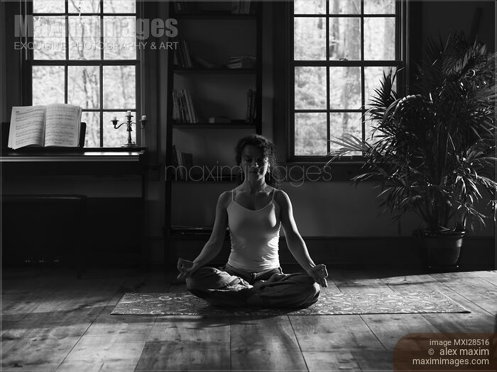 Woman meditating at home in dramatic dim light black and white Stock photo of Woman meditating at home in dramatic dim light black and white Buy commercial use license at MaximImages