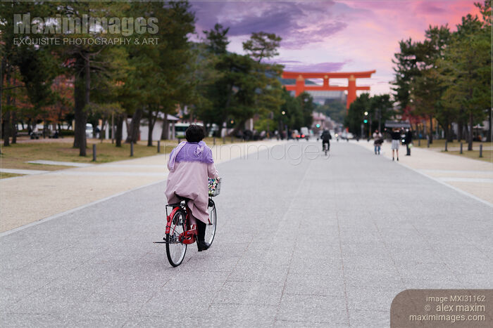 Stock photo of Woman on a bicycle riding towards Torii gate of Heian Shinto Shrine in Kyoto Buy commercial use license at MaximImages