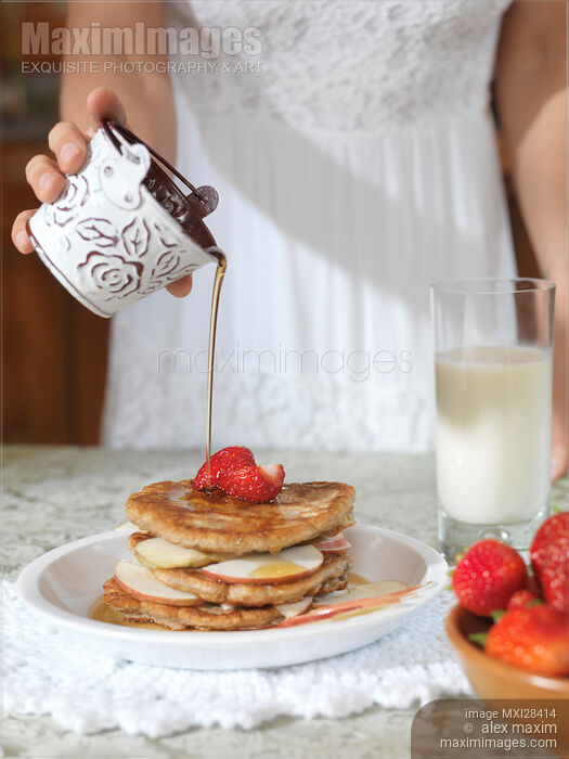 Stock photo of Woman pouring maple syrup on pancakes Buy commercial use license at MaximImages
