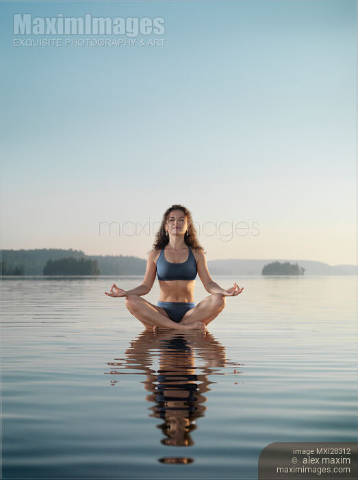 Woman practicing meditation sitting on platform in the water Stock photo of Woman practicing meditation sitting on platform in the water Buy commercial use license at MaximImages