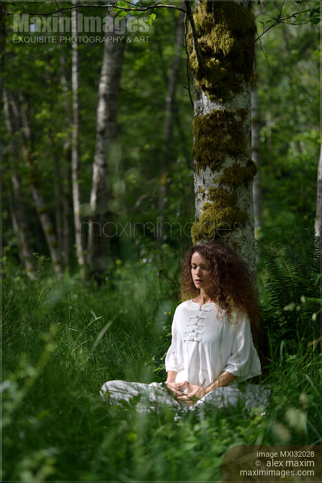 Woman practicing sitting meditation leaning against a birch tree in green forest Stock photo of Woman practicing sitting meditation leaning against a birch tree in green forest Buy commercial use license at MaximImages