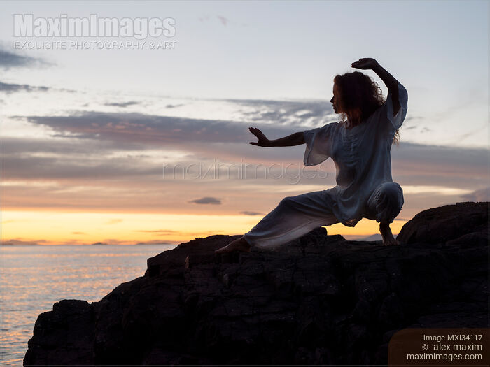 Woman practicing Tai Chi at rocky sea shore during sunset Stock photo of Woman practicing Tai Chi at rocky sea shore during sunset Buy commercial use license at MaximImages