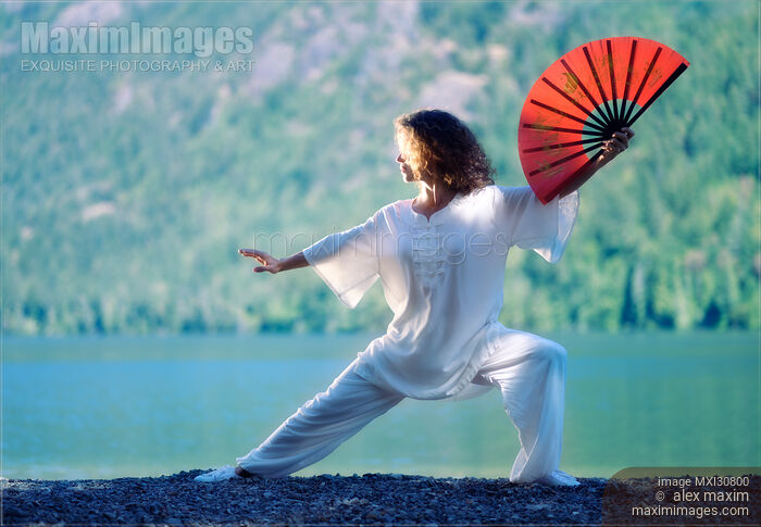 Woman practicing Tai Chi with a fan in sunrise in the nature Stock photo of Woman practicing Tai Chi with a fan in sunrise in the nature Buy commercial use license at MaximImages
