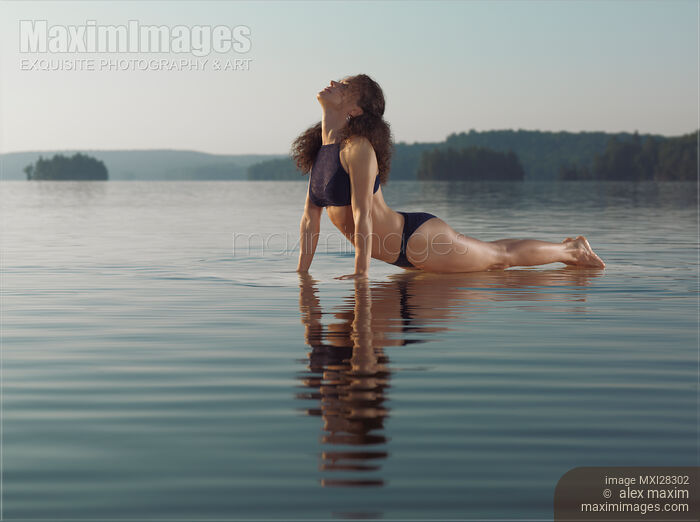 Stock photo of Woman practicing yoga in the water Upward Facing Dog posture Buy commercial use license at MaximImages