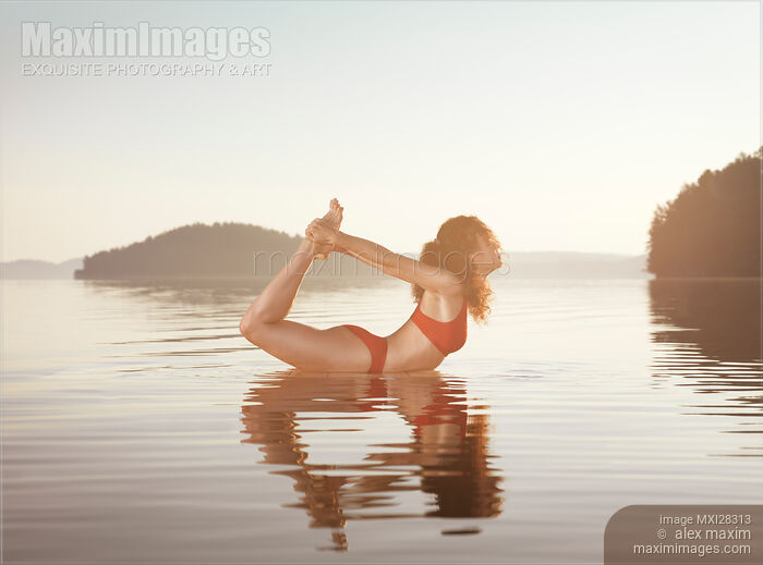 Woman practicing yoga on platform in the water Bow Dhanurasana pose Stock photo of Woman practicing yoga on platform in the water Bow Dhanurasana pose Buy commercial use license at MaximImages