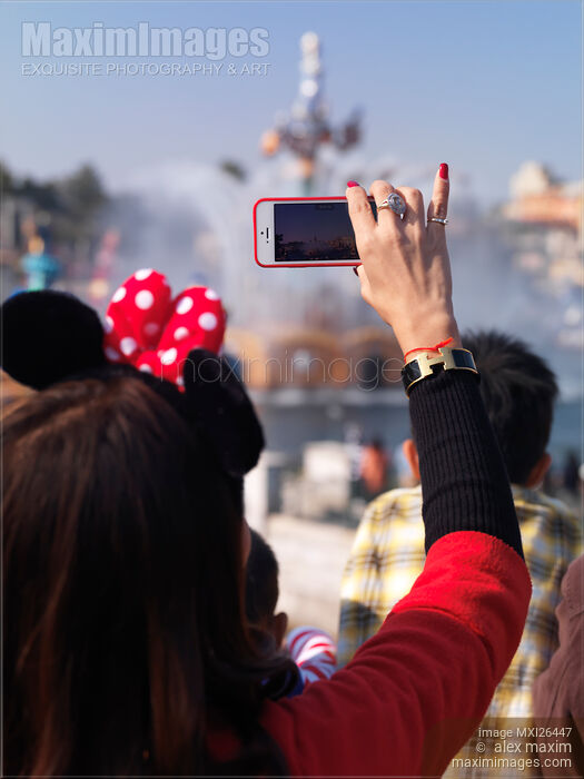 Woman recording a show with her iPhone at Tokyo Disneysea Stock photo of Woman recording a show with her iPhone at Tokyo Disneysea Buy commercial use license at MaximImages