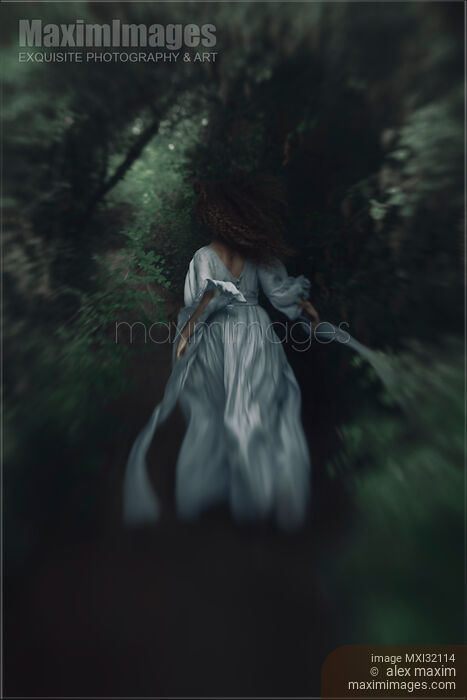 Woman running away into a deep dark forest in her long dress flowing behind Stock photo of Woman running away into a deep dark forest in her long dress flowing behind Buy commercial use license at MaximImages