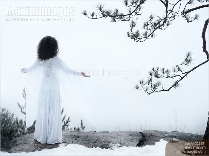Woman standing on a cliff with spread hands embracing the world Stock photo of Woman standing on a cliff with spread hands embracing the world Buy commercial use license at MaximImages
