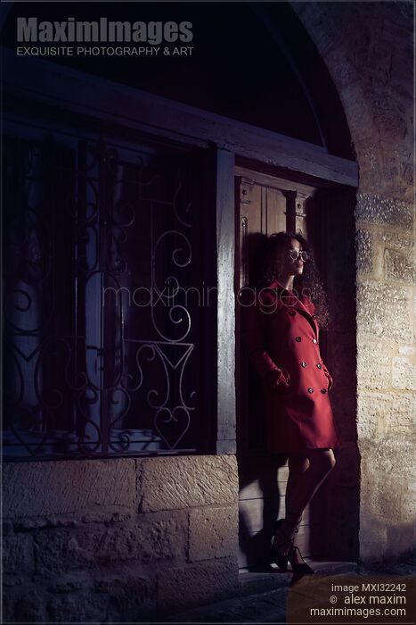 Woman standing on the street at night leaning against a locked door of an old house Stock photo of Woman standing on the street at night leaning against a locked door of an old house Buy commercial use license at MaximImages