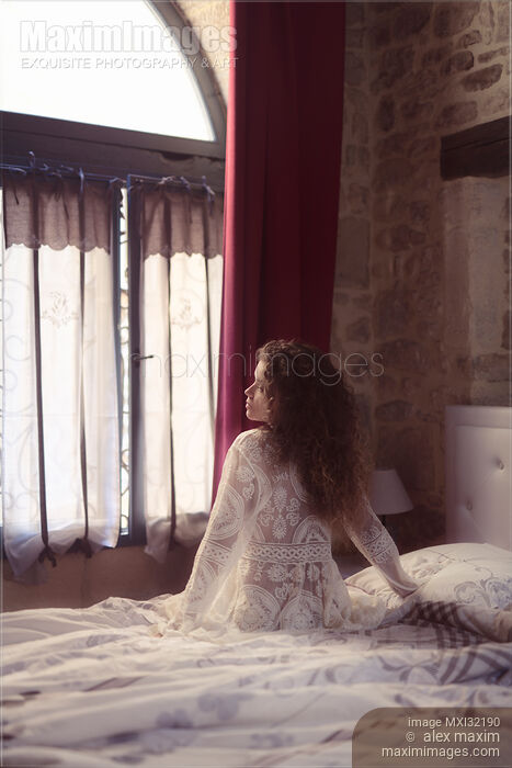Woman thoughtfully sitting on the side of a bed in French bedroom in white nightgown Stock photo of Woman thoughtfully sitting on the side of a bed in French bedroom in white nightgown Buy commercial use license at MaximImages