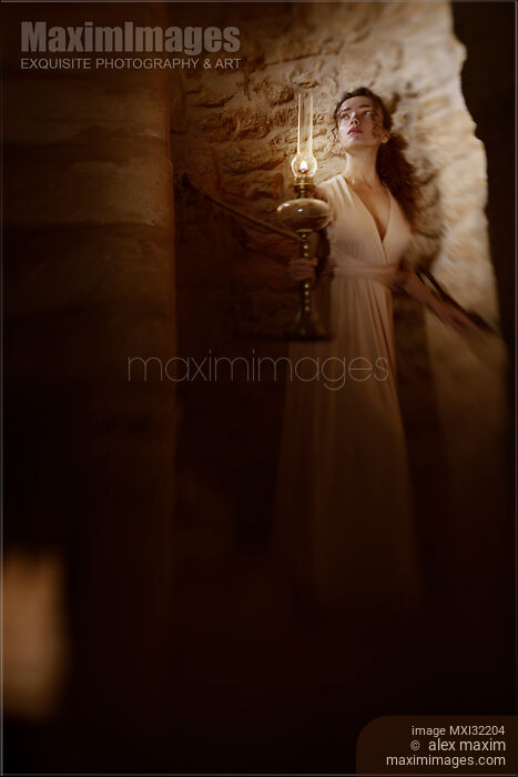 Woman walking down a dark spiral staircase with an oil lamp in her hand looking cautiously upstairs Stock photo of Woman walking down a dark spiral staircase with an oil lamp in her hand looking cautiously upstairs Buy commercial use license at MaximImages
