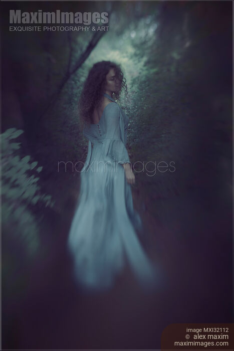 Woman walking into a forest looking back over her shoulder Stock photo of Woman walking into a forest looking back over her shoulder Buy commercial use license at MaximImages
