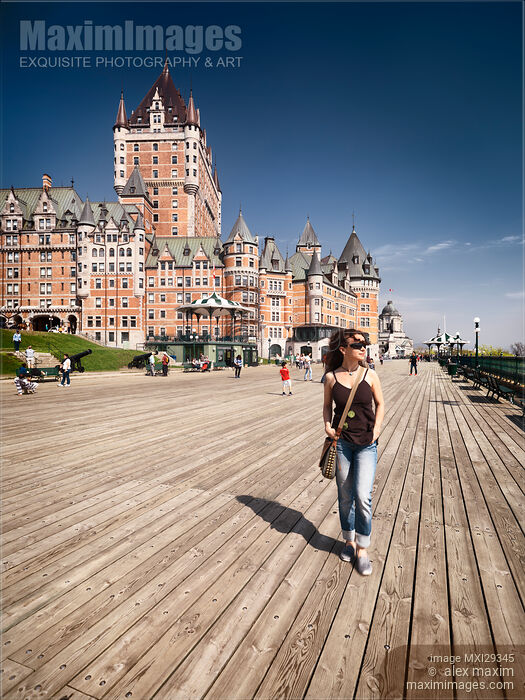 Stock photo of Woman walking on Dufferin terrace by the Fairmont Le Chateau Frontenac castle in old Quebec city Buy commercial use license at MaximImages