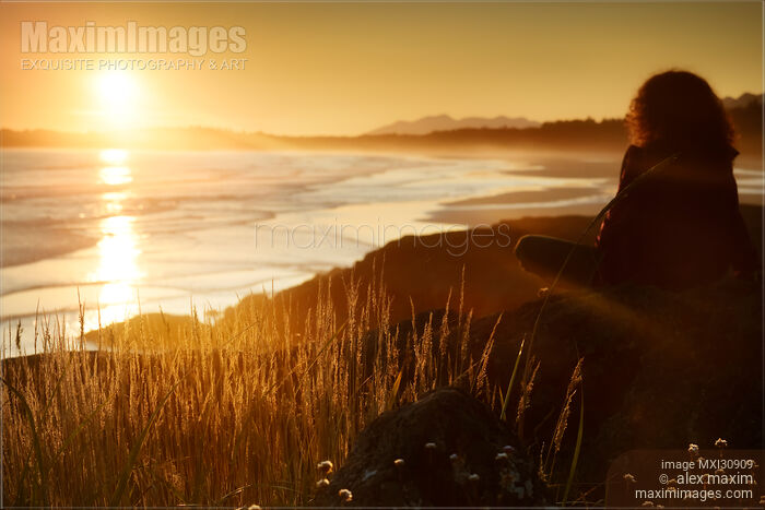 Stock photo of Woman watching beautiful sunset on a shore of Pacific Rim National Park Tofino BC Canada Buy commercial use license at MaximImages