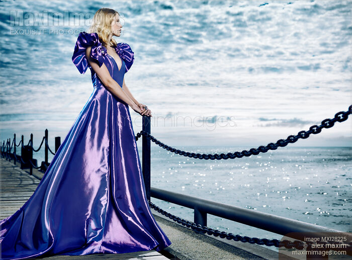 Woman wearing beautiful long blue dress standing at waterfront Stock photo of Woman wearing beautiful long blue dress standing at waterfront Buy commercial use license at MaximImages