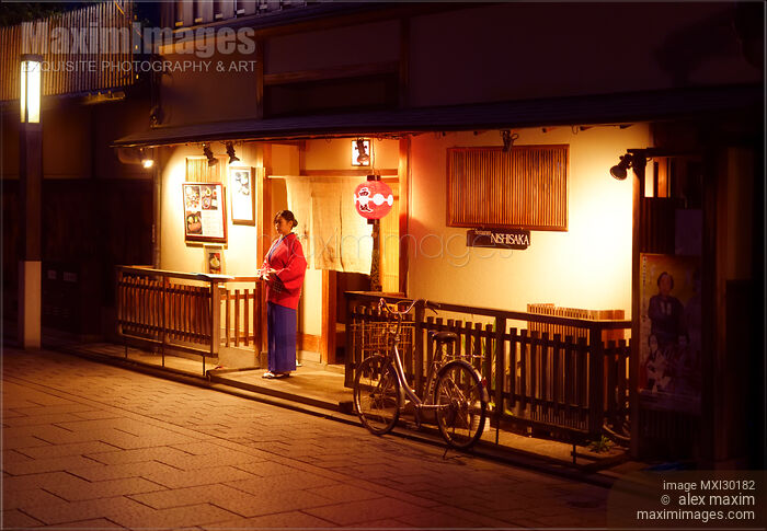 Stock photo of Woman welcoms guests by the entrance of traditional Japanese restaurant Nishisaka at night in Gion Kyoto Buy commercial use license at MaximImages