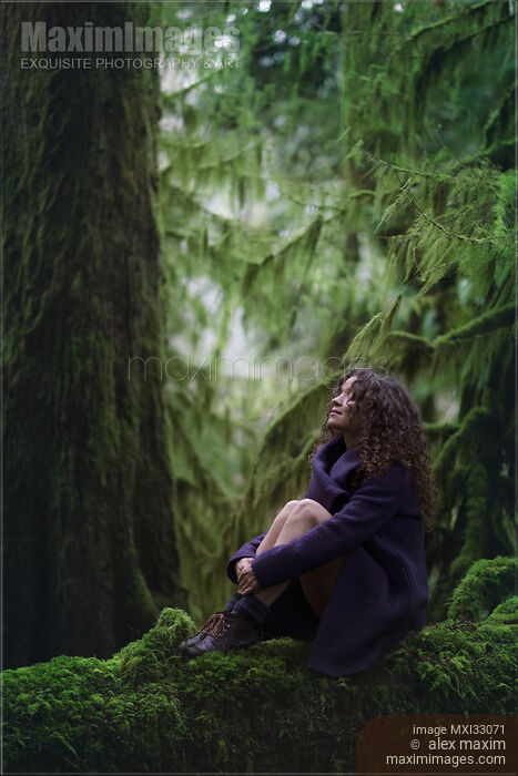 Woman with a dreamy expression sitting on a mossy tree trunk in ancient green forest moody nature scenery Stock photo of Woman with a dreamy expression sitting on a mossy tree trunk in ancient green forest moody nature scenery Buy commercial use license at MaximImages