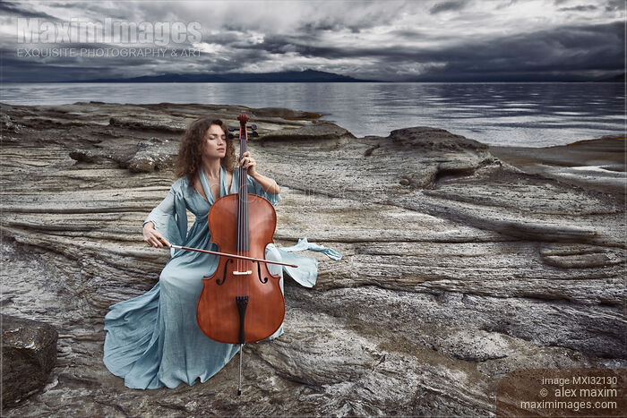 Stock photo of Woman with a tranquil thoughtful expression gracefully playing cello in dramatic stormy ocean shore scenery Buy commercial use license at MaximImages