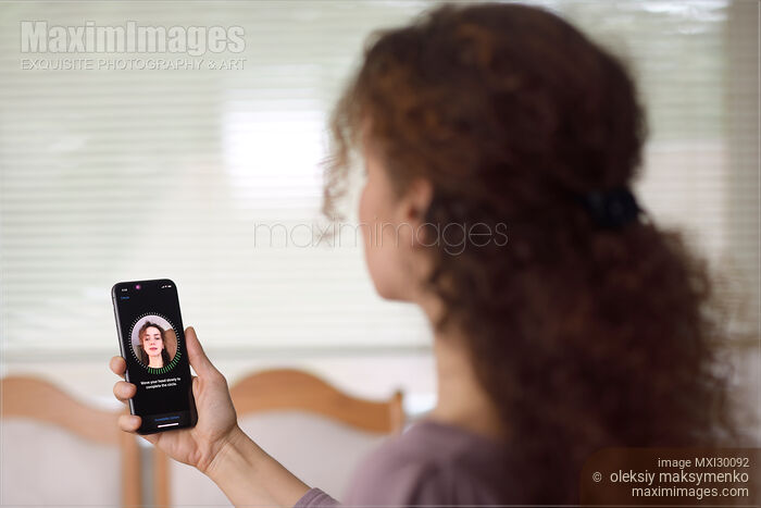 Woman with Apple iPhone X in her hand setting up Face ID Stock photo of Woman with Apple iPhone X in her hand setting up Face ID Buy commercial use license at MaximImages