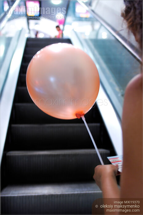 Stock photo of Woman with balloon on escalator Buy commercial use license at MaximImages