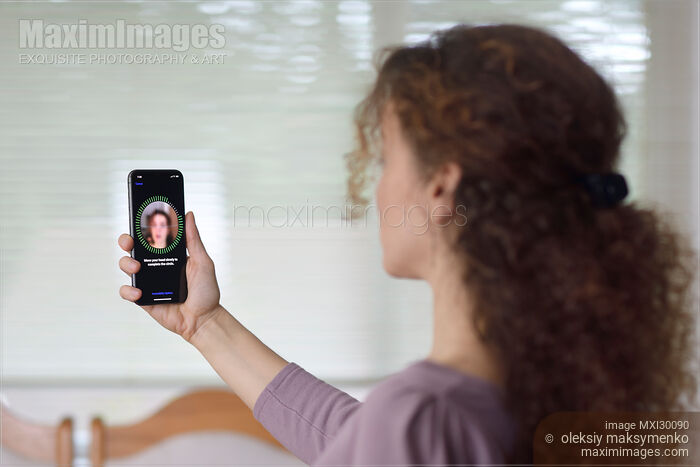 Woman with iPhone X setting up Face ID biometric authentication Stock photo of Woman with iPhone X setting up Face ID biometric authentication Buy commercial use license at MaximImages